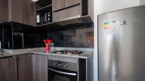 Une cuisine moderne avec des meubles en bois foncé, des appareils en acier inoxydable et un four à micro-ondes encastré.