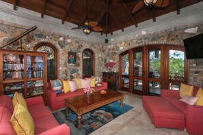 A cozy living room with a stone wall, a bookshelf, a red sofa, and a wooden coffee table.