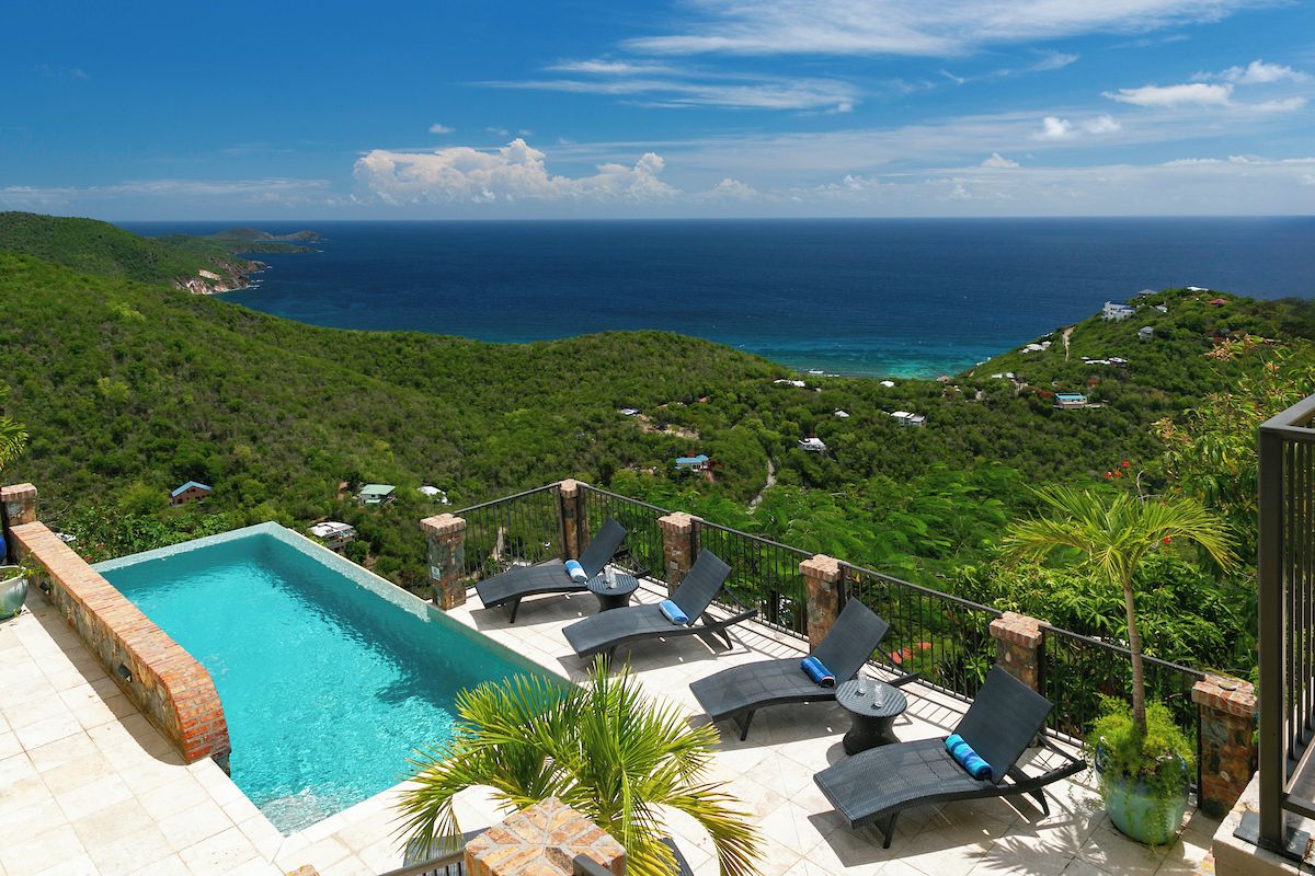 A rooftop pool with lounge chairs and a view of the ocean.