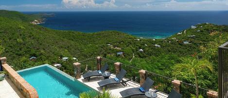 A rooftop pool with lounge chairs and a view of the ocean.