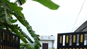 Una entrada cerrada a una zona residencial con un sendero de concreto que conduce a una casa blanca con un balcón.