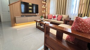 A modern living room with a flat-screen TV mounted on a wooden wall, a sofa with patterned cushions, and a wooden coffee table. - 4-bedroom house in enchanting San Fernando with WiFi, AC (San Fernando)