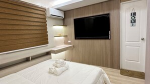 A modern hotel room with a large bed, a flat-screen TV mounted on the wall, a bedside table, and a door with a 'LOVE' sign. - 4-bedroom house in enchanting San Fernando with WiFi, AC (San Fernando)