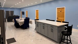 A modern kitchen with a marble countertop, grey cabinets, and a dining area with a table and chairs. - 4-bedroom house in nice Georgetown with WiFi, AC. Enjoy your stay (Georgetown)