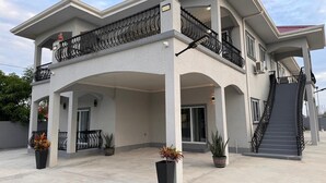 A two-story house with a balcony, a staircase, and potted plants. - 4-bedroom house in nice Georgetown with WiFi, AC. Enjoy your stay (Georgetown)
