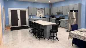 A modern kitchen with a central island, grey cabinets, and a stainless steel refrigerator. - 4-bedroom house in nice Georgetown with WiFi, AC. Enjoy your stay (Georgetown)