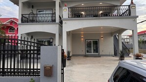 A two-story house with a covered entrance, a balcony, and a gated driveway. - 4-bedroom house in nice Georgetown with WiFi, AC. Enjoy your stay (Georgetown)