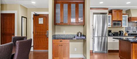 A modern kitchen with wooden cabinets, a stainless steel refrigerator, and a dining area with wicker chairs.