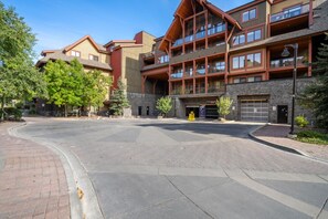 A multi-story hotel with a stone facade, balconies, and a parking area.