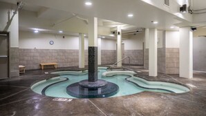 A swimming pool with a central fountain, tiled walls, and a bench. - Rockies Base: Hot Tub, Pool & National Park Pass (Canmore)