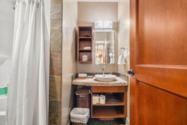 A bathroom with a wooden door, a white sink, a mirror, and a towel rack.