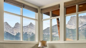 A room with a mountain view, a lamp, and two leather sofas. - Three Sisters View with Hot Tub, Pool & BBQ (Canmore)