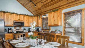 Una cocina de madera con una mesa de comedor preparada para cuatro personas, con un arreglo central de orquídeas.