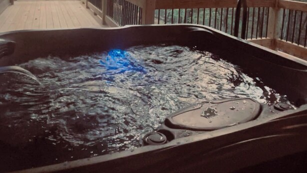 Un jacuzzi en una terraza de madera con vista a un bosque.