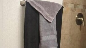 A bathroom with a towel rack holding two towels, a light switch, and a door with a brass handle. - Beautiful private room, garden! (Yuma)