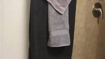 Een douche, handdoeken, zeep, toiletpapier