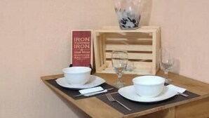 A wooden dining table with two stools, a vase, and a sign on the wall. - Beautiful private room, garden! (Yuma)