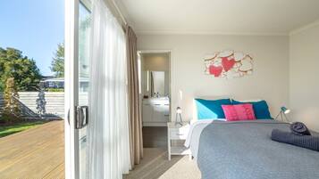 A bedroom with a bed, a nightstand, a mirror, and a view of the outdoors.