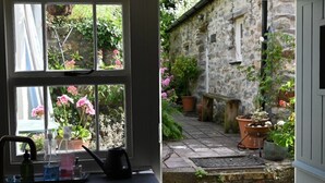 Vista a través de una ventana hacia un edificio de piedra con jardín.