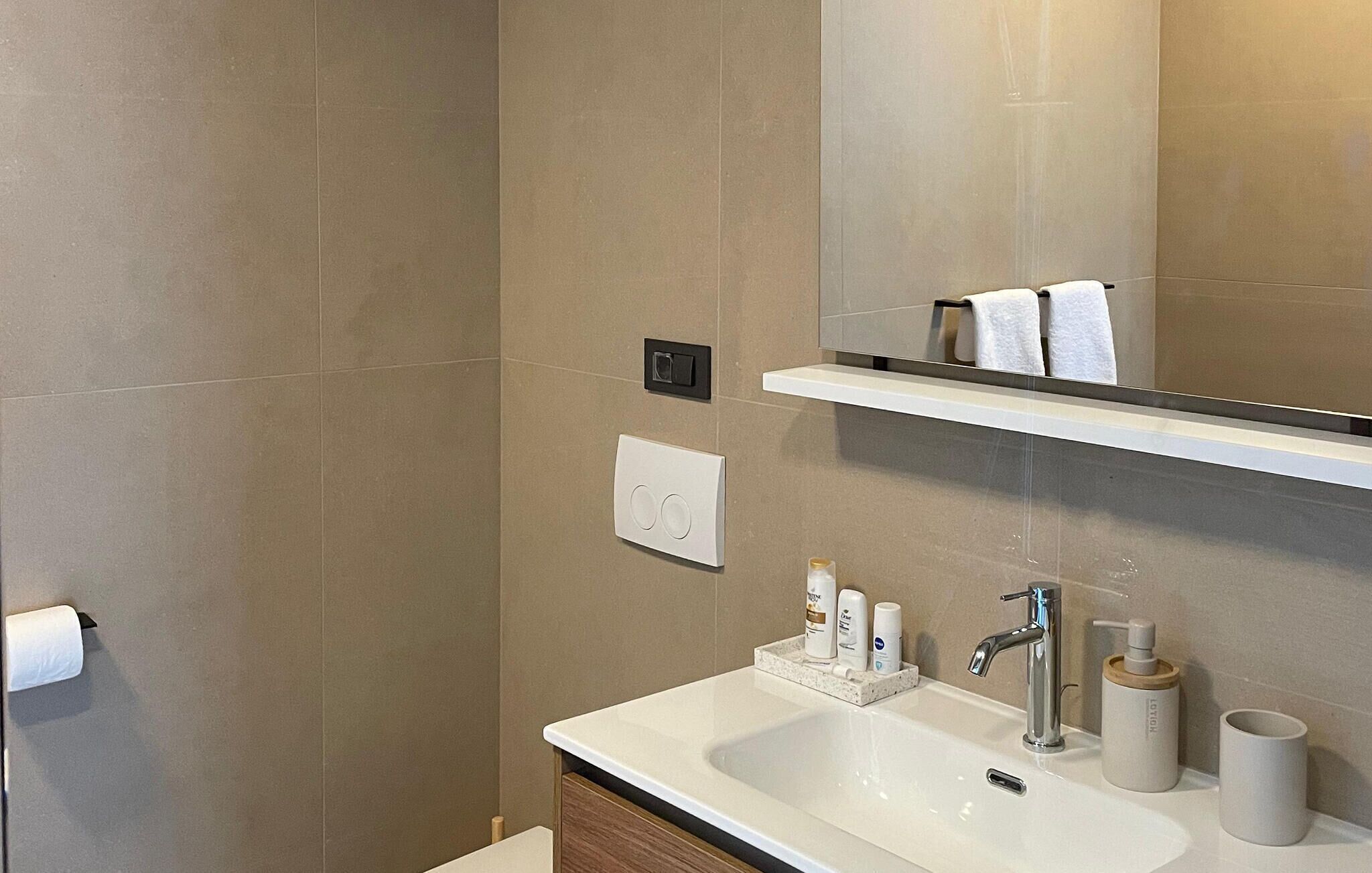 Uma casa de banho moderna com lavatório, espelho, porta-toalhas e artigos de higiene pessoal.