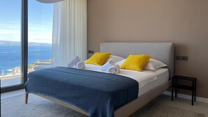 A modern hotel room with a large bed, two pillows, a bedside table, and a view of the sea. - Stunning home in Podgora (Podgora)