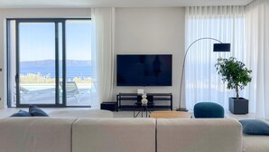 A modern living room with a large flat-screen TV, a sofa, a coffee table, and a potted plant. - Stunning home in Podgora (Podgora)