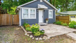 A single-story house with a dark blue exterior, white trim, and a front door. - Charming 3-Bedroom House with WiFi, AC & Hot Tub in Brilliant Crystal Beach (Fort Erie)