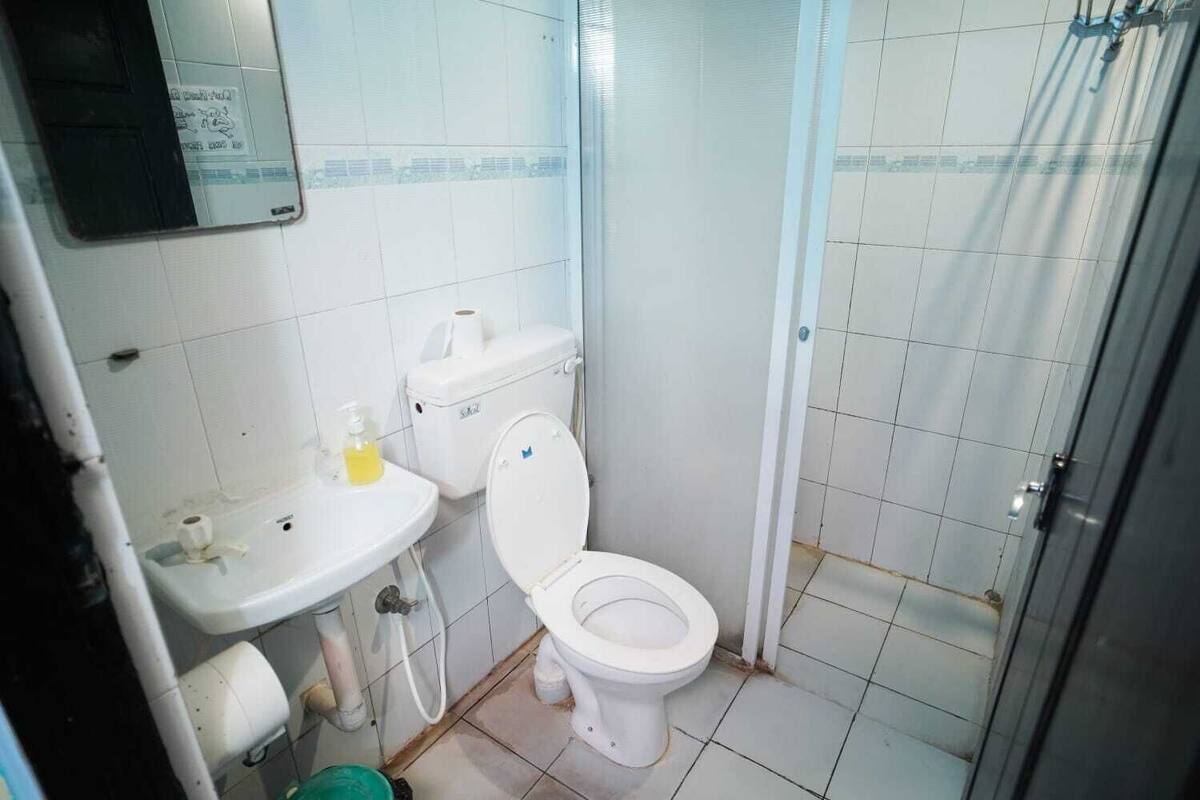 Casa de banho pequena e compacta, com sanita, lavatório e chuveiro.