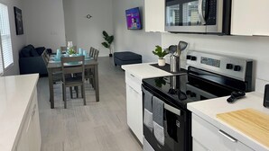 Une cuisine moderne équipée d’un four à micro-ondes, d’un four et d’une planche à découper en bois posée sur le plan de travail.