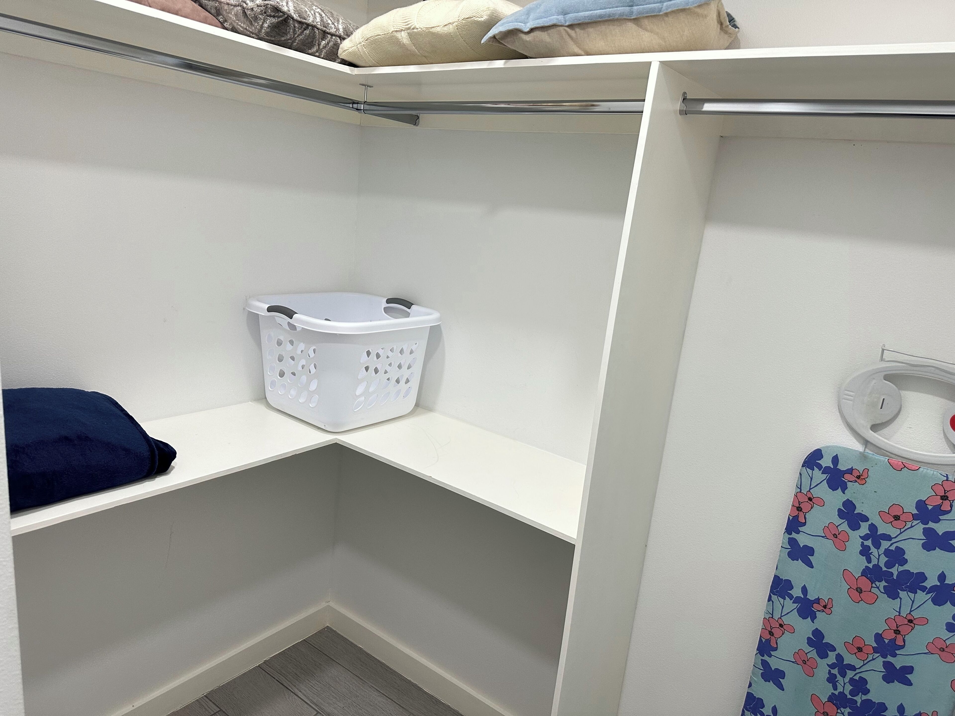 A laundry basket on a white shelf, a blue and pink patterned towel, and a white wall.