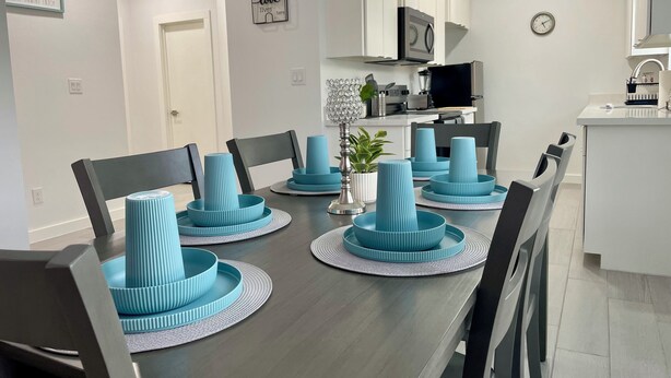 Un espace repas moderne avec une table en bois foncé, des assiettes bleues à motifs en relief et des chaises noires.