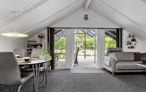 Una habitación acogedora en el desván, con zona de comedor, sofá y estantería.