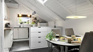 Een moderne keuken met witte kastjes, een eettafel met stoelen en een dakraam erboven.