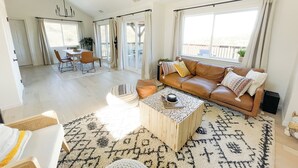 A spacious living room with a brown leather sofa, a wooden coffee table, and a patterned rug.