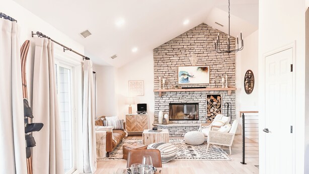 A cozy living room with a fireplace, comfortable seating, and a dining area with a table set for two.