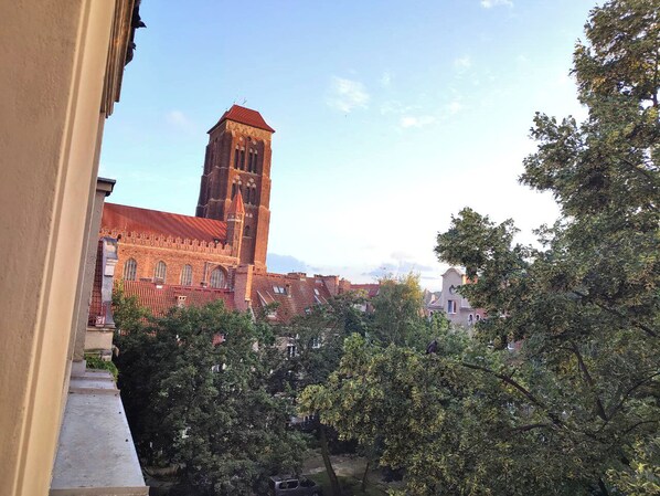 A view of a red brick building with a tall tower, surrounded by trees and other buildings.