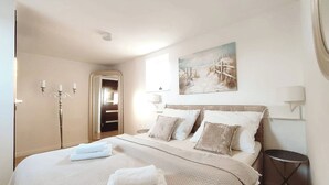 Une chambre à coucher avec un lit, des lampes de chevet, un tableau et une porte.