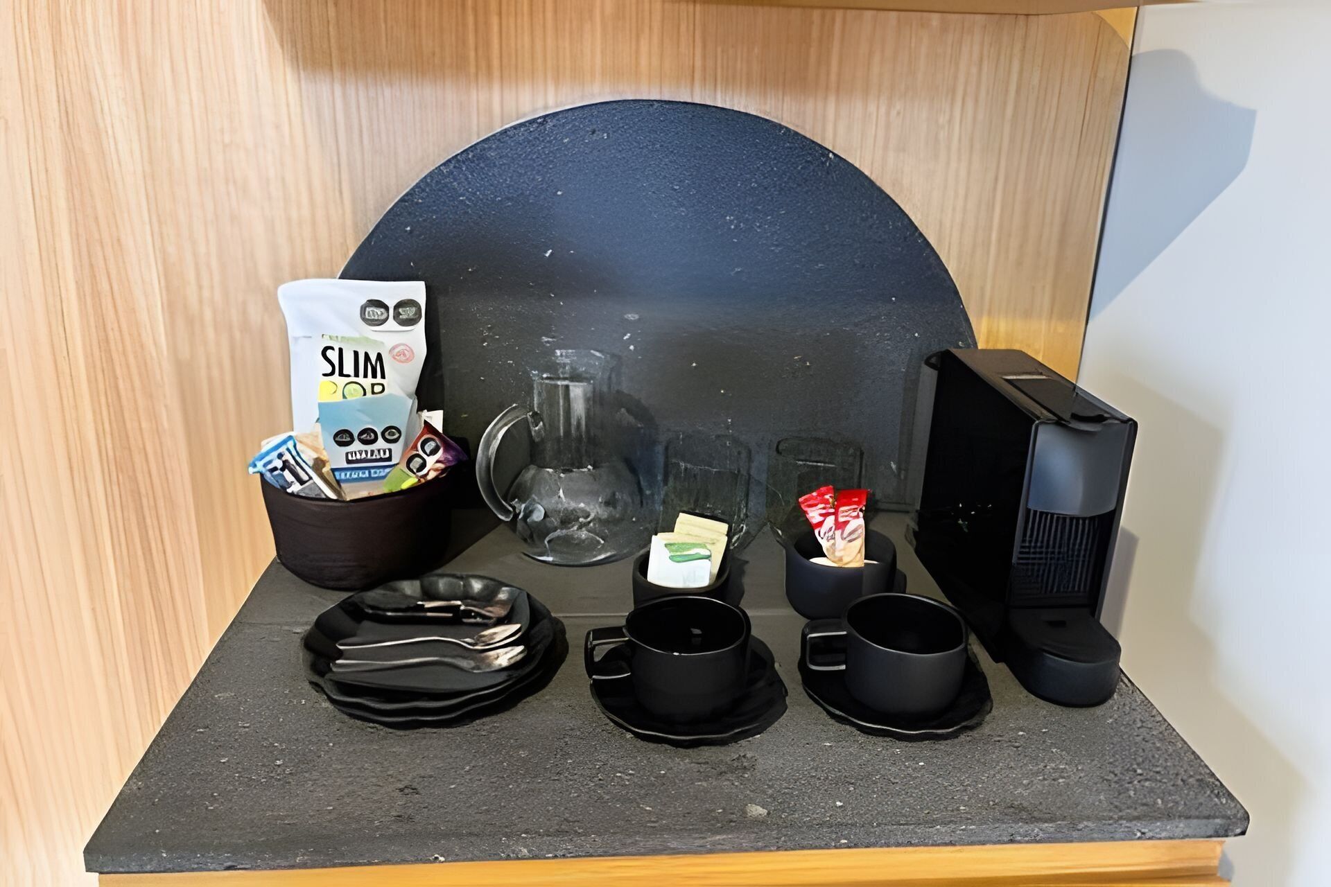 A kitchenette with a coffee maker, a kettle, and a bag of Slim Food snacks.