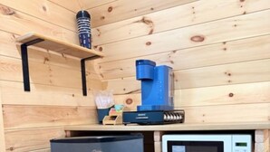 A compact kitchenette with a black refrigerator, a microwave, and a coffee maker on a wooden countertop.