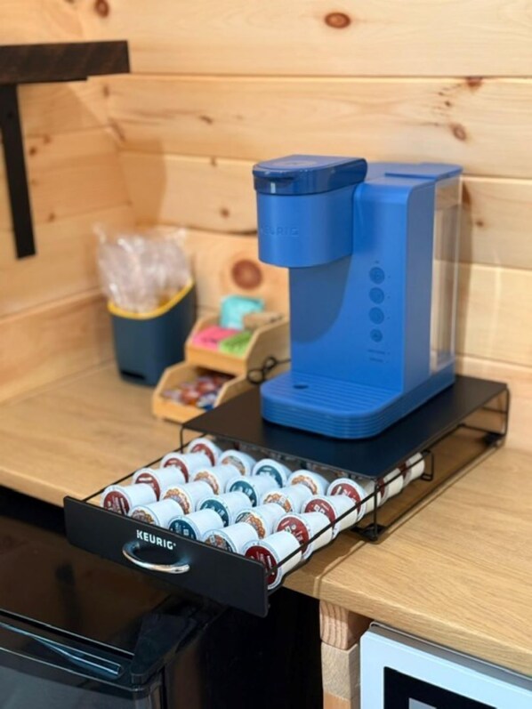 A coffee machine on a wooden counter with a coffee pod holder below it.