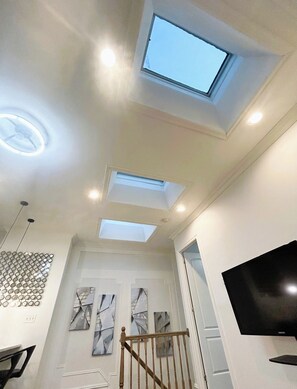 Un interior moderno con tragaluces, iluminación empotrada y una televisión de pantalla plana.