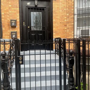 Una reja de metal negro que da a un edificio de ladrillo con puertas numeradas.