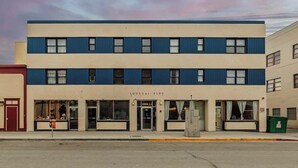 Un edificio de dos pisos con fachada plana, ventanas grandes y un letrero que dice "LOUSSA C BLDG".