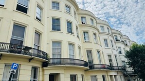 A row of cream-colored buildings with balconies and a parking sign. - Hove Alone 5 Top Floor By My Getaways (Hove)