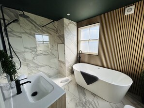Een moderne badkamer met een vrijstaand bad, een douchegedeelte en een wastafel.