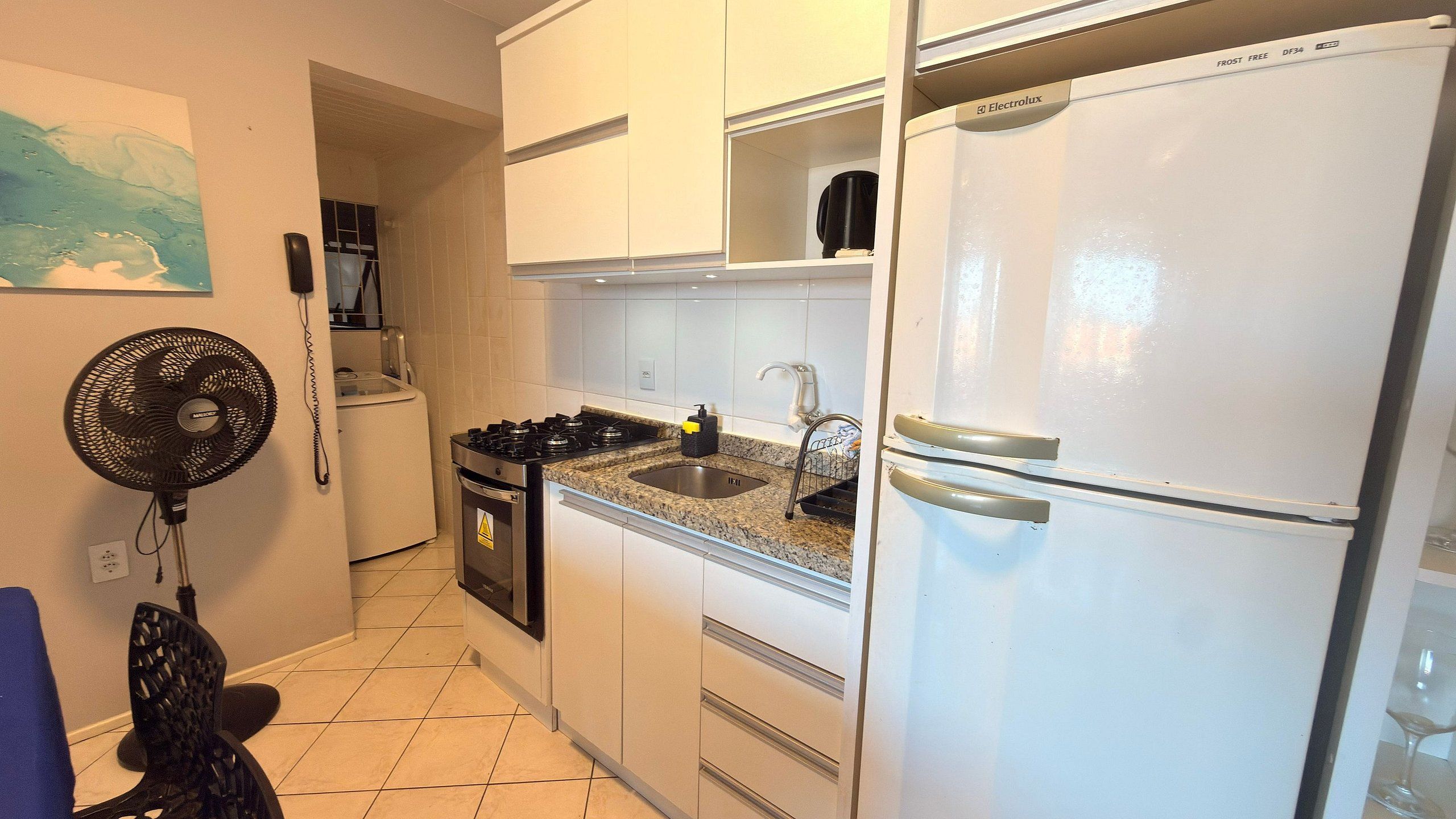 A kitchen with white cabinets, a granite countertop, a stove, a sink, and a refrigerator.