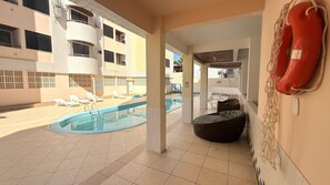 A swimming pool area with lounge chairs, a lifebuoy, and a tiled floor. - Aguas de Marco  (Florianopolis)