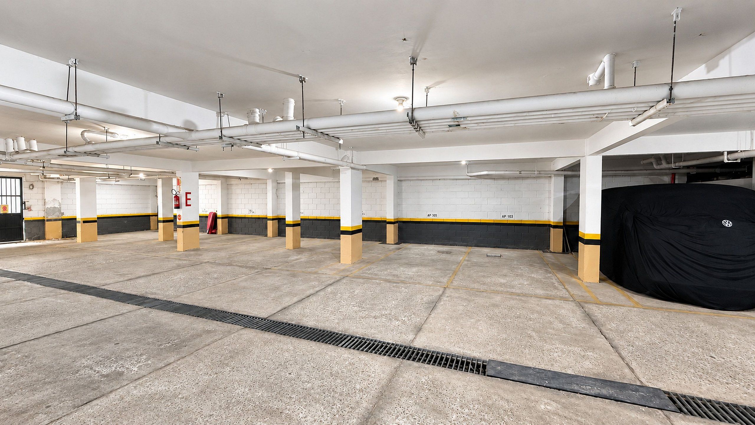Un amplio estacionamiento con varios niveles, pisos de concreto y un desagüe central.