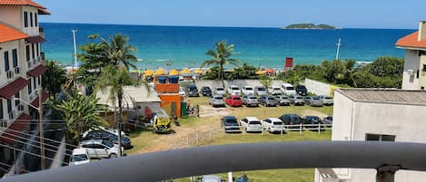 A coastal view with a parking lot, buildings, and a clear blue sea.