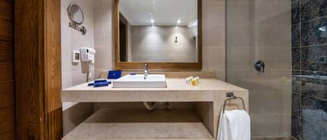 A modern bathroom with a large mirror, a sink, a towel rack, and a shower area.